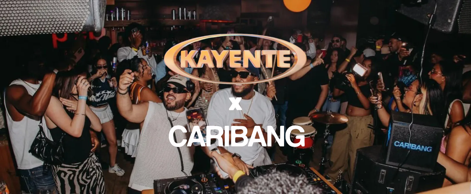 Mensen dansen in de club, met de logo's van Kayente en Caribang