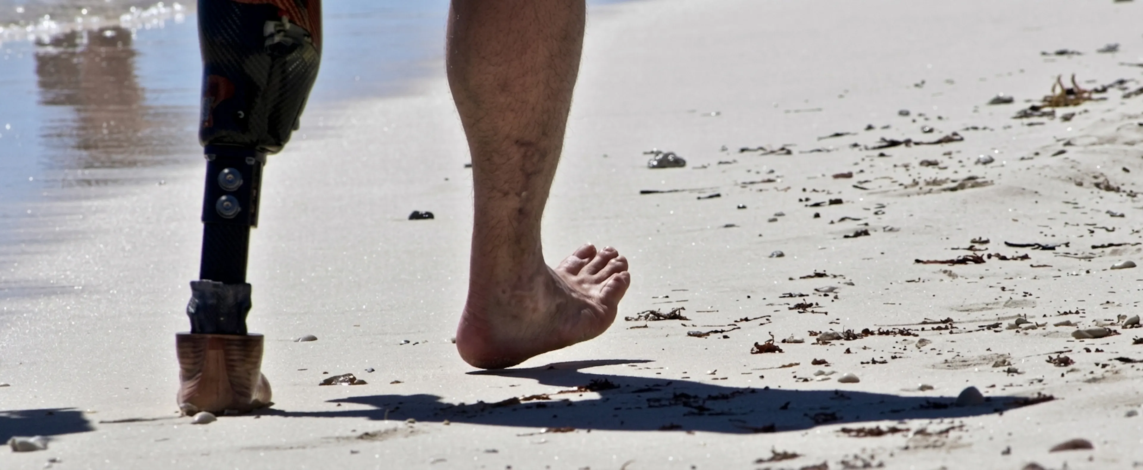 Man op het strand met een beenprothese