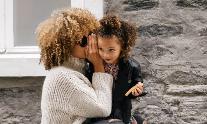 The value of family hearing care represented by mom whispering to child