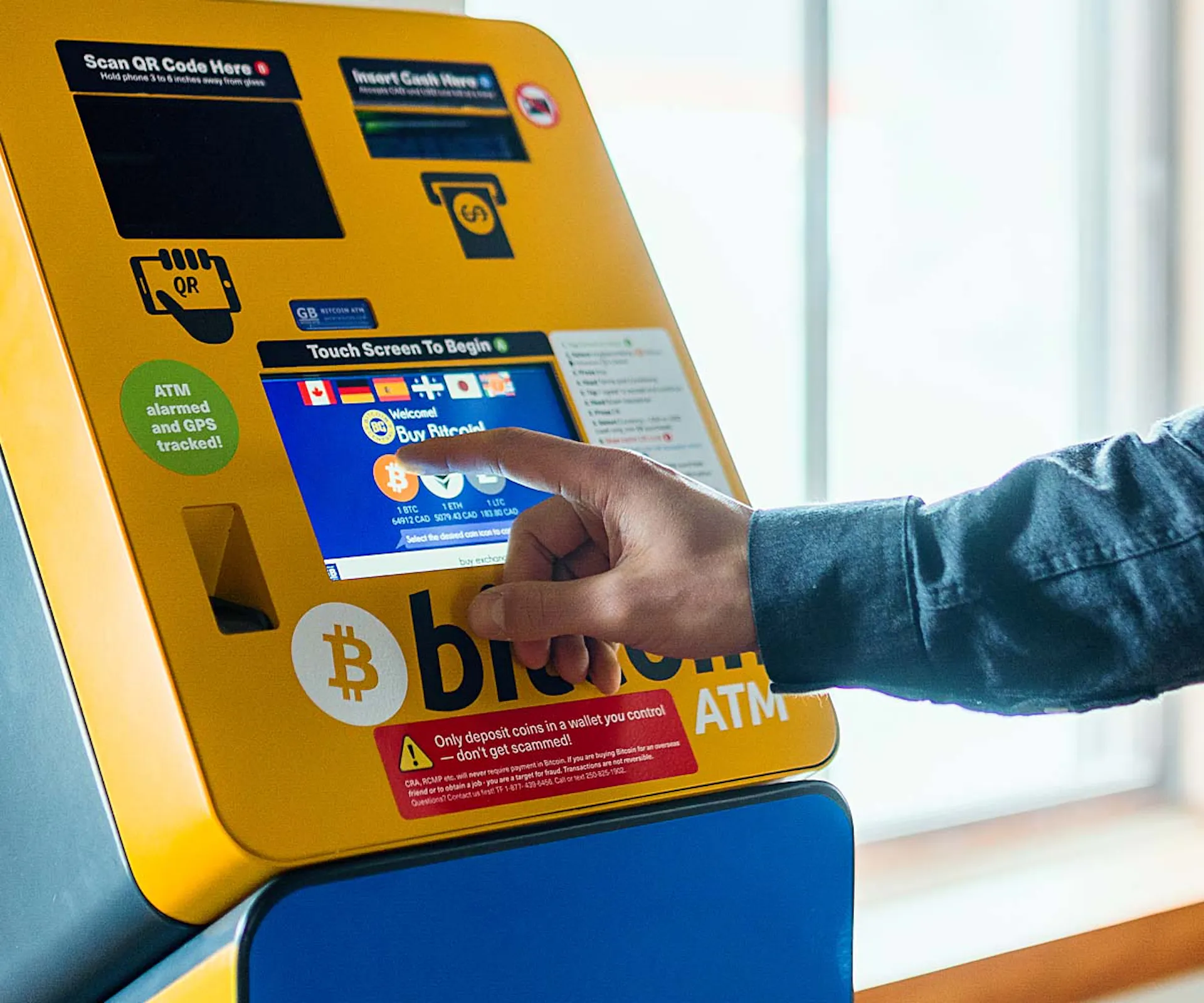 hand pressing screen on crypto atm machine