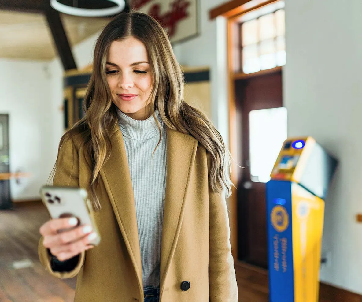 Woman holding phone in front of BitCoin Central ATM.