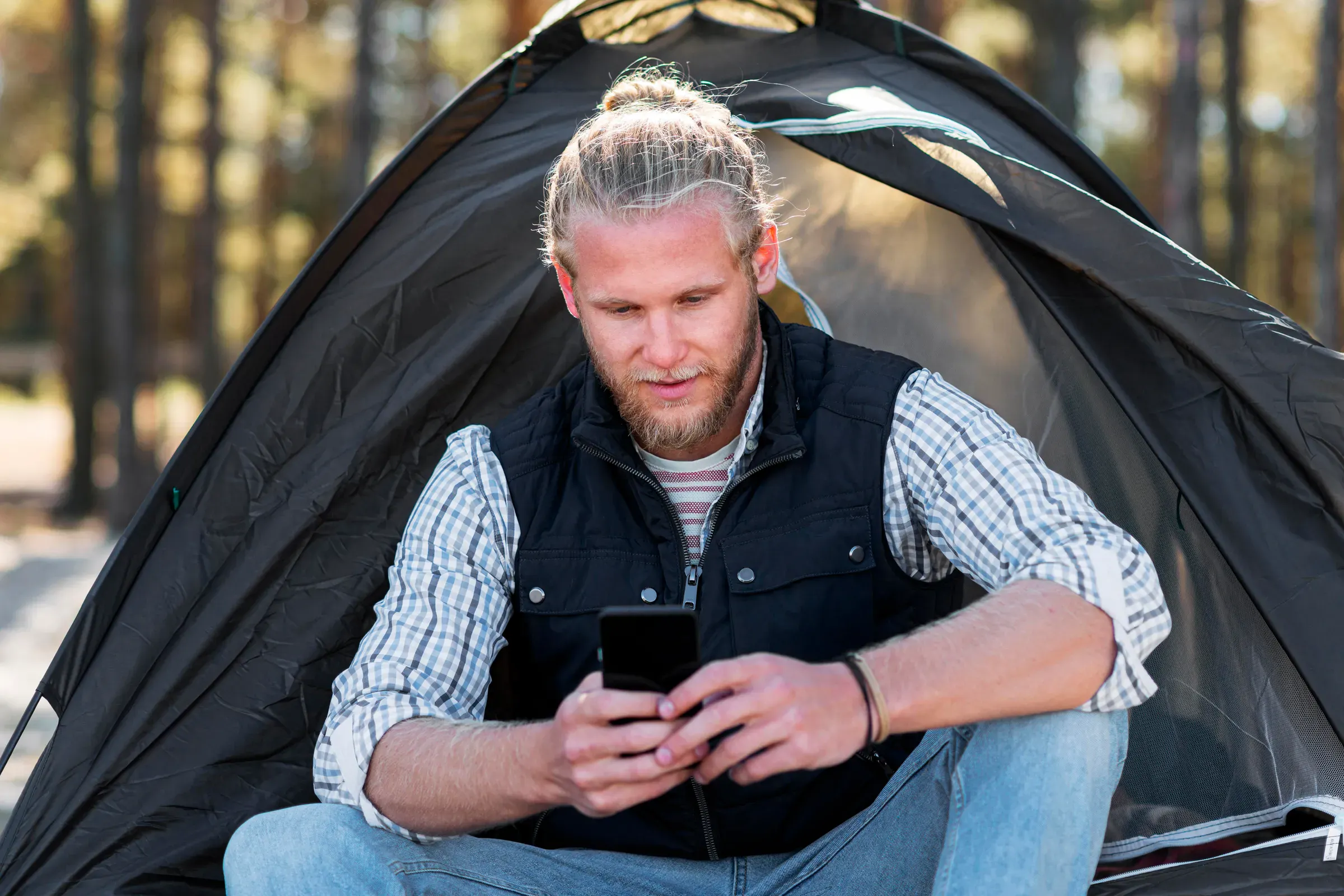 Man använder mobilen framför tältet