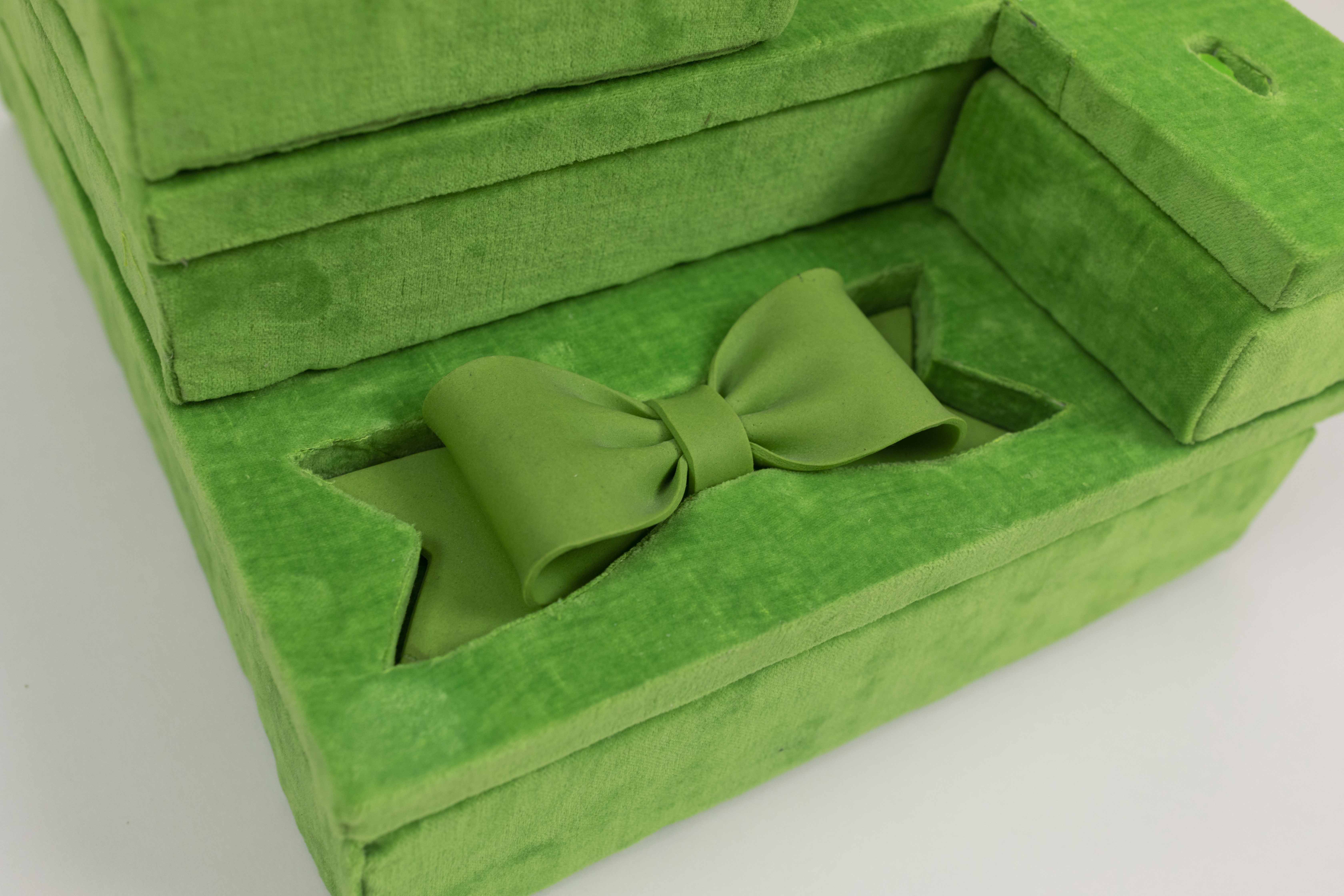 Image caption: Adam Milner, "Lime Green Apple Museum Display" (detail), 2021, found nail, plastic shards, and gum paste bow, hand-dyed velvet, birch, oil paint, found Styrofoam and polystyrene, brass wire and soldering.