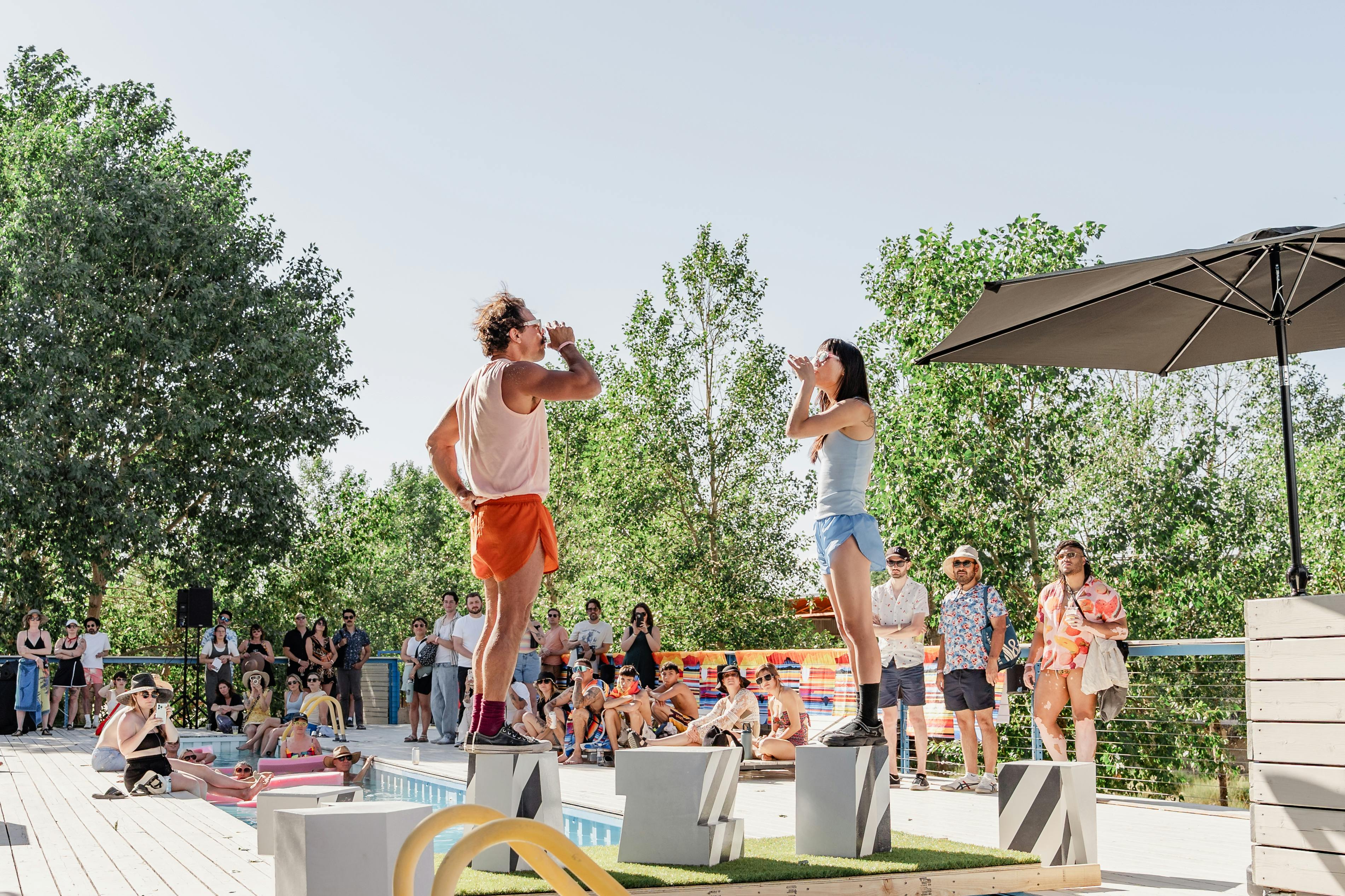 Elle Hong in collaboration with Joshua Ware, "HOW WE DO THINGS," 2025, performance with two dancers, two glasses, pitchers, 4' x 10' wooden platforms, 5 stools, text by Gertrude Stein. Commissioned for "flood" at TAXI Campus in Denver, Colorado. Courtesy of the artists and Black Cube Nomadic Art Museum. Photo by From the Hip Photo.
