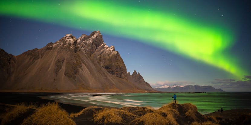 A loan hiker observes the northern lights in Iceland wearing Black Diamond apparel.  