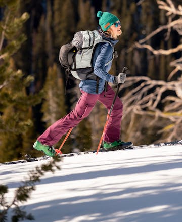 L'athlète Black Diamond Mary McIntyre part pour une randonnée à ski par une journée de printemps ensoleillée portant le pantalon Dawn Patrol pour femme.