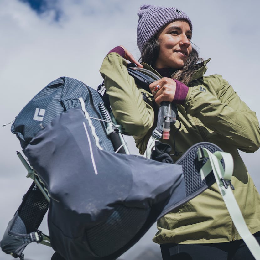 A hiker pulls on her Pursuit 30 pack, ready for a hike. 