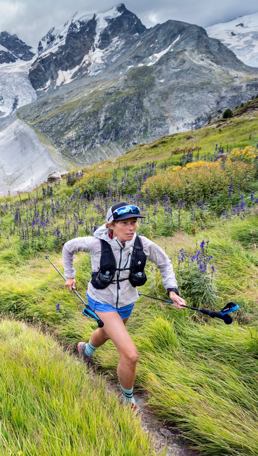 Kim Strom running in the alps with Black Diamond Distance series running poles, wind shell, and pack. 
