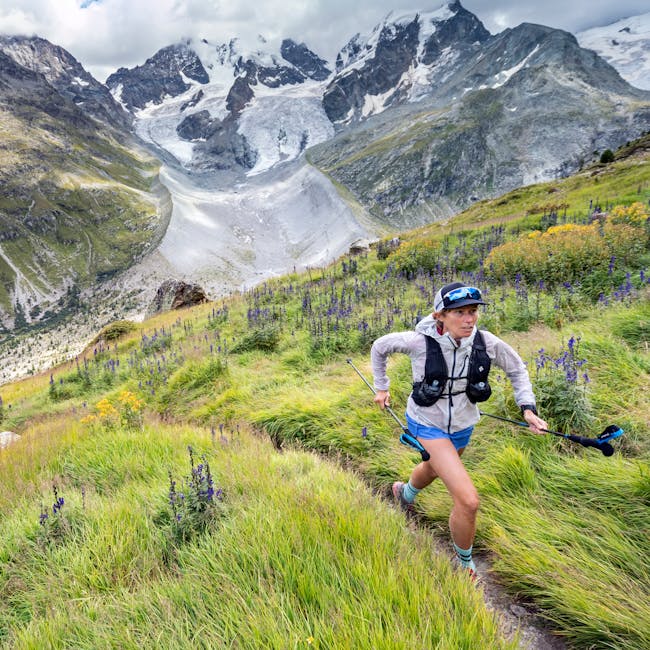 Kim Strom running in the alps with Black Diamond Distance series running poles, wind shell, and pack.