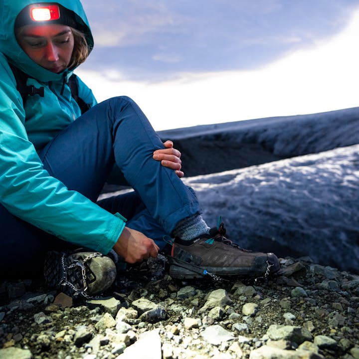 "A hiker gets ready to traverse icy terrain with the Black Diamond Blitz traction device."