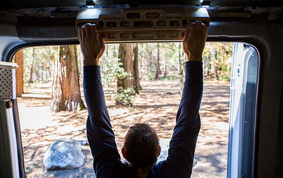 Alex Honnold hangboards in his van while checking out the scenery outside.