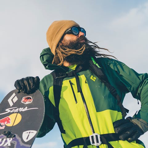 Black Diamond Athlete John Jackson leans on his splitboard wearing his signature collection.