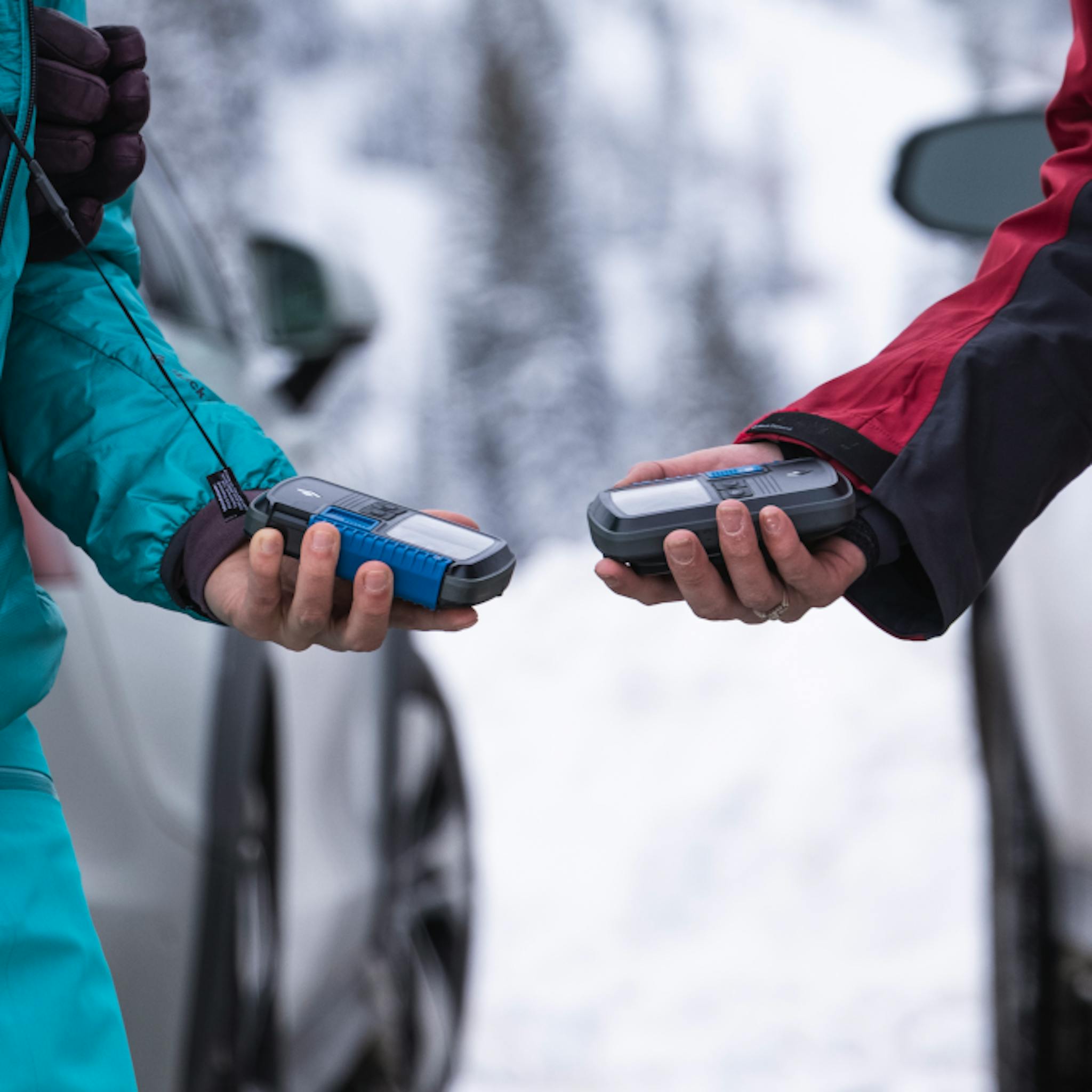 Two skiers holding the Guide Beacon and doing a check