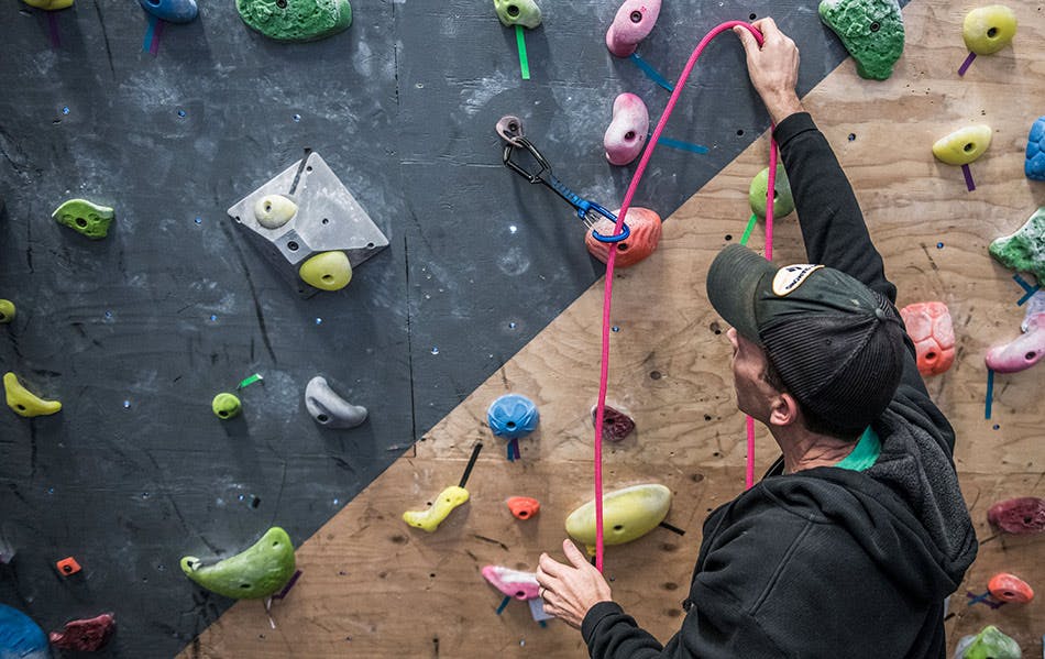 Image of Kolin Powick demonstrating how to feed a rope through a quickdraw.