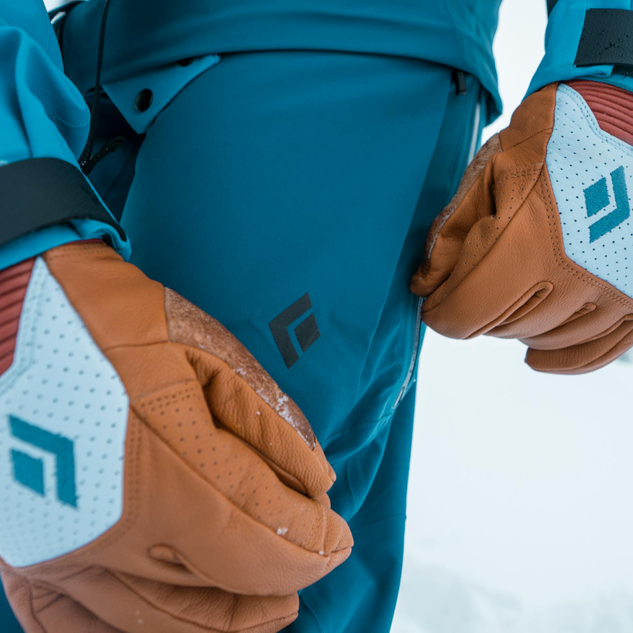 A skier in BD Impulse gloves opens the air vents on her Recon Stretch Bibs.