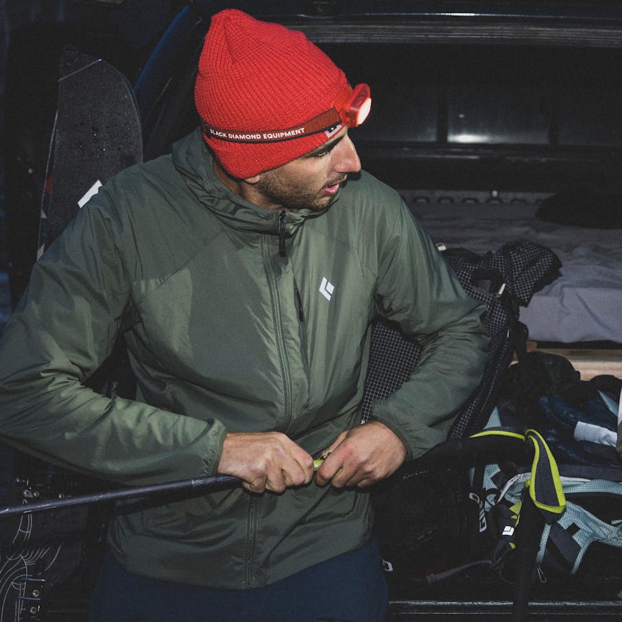A backcountry skier wearing the Alpine Start Insulated Hoody for a Dawn Patrol.