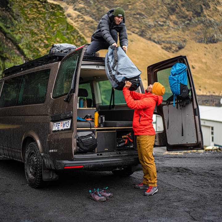 Black Diamond Ambassador Andrew King helps a friend unloading the Stonehauler Duffel off the roof of a camper van. 