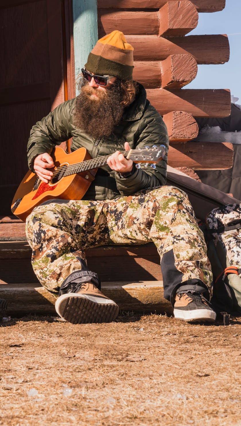 The Jackson brothers sit on the steps of their cabin and play music in their Black Diamond Down Jackets.