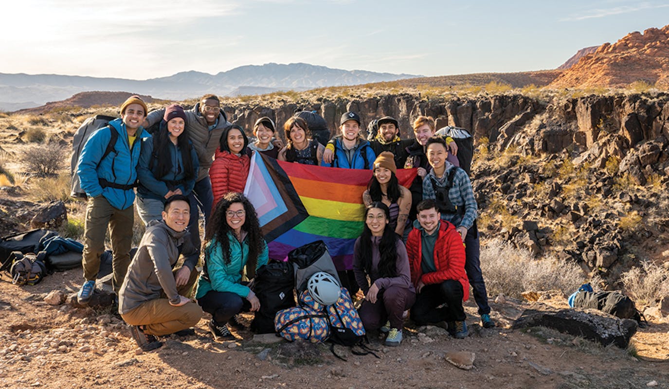 Climbers standing in front of a PRIDE flag.