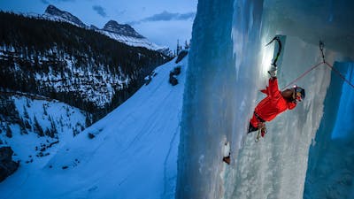 Person ice climbing at night wearing a headlamp