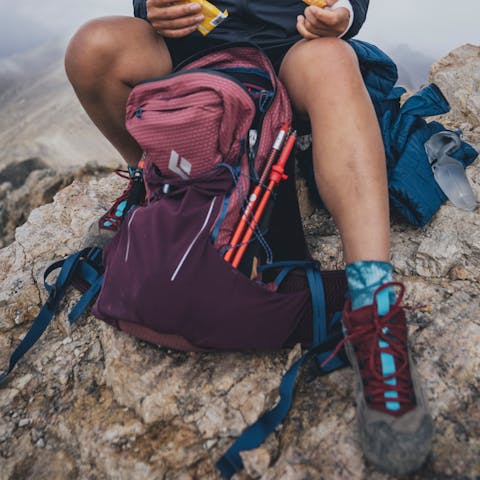 A hiker pulls a snack out of her Pursuit 30 pack. 