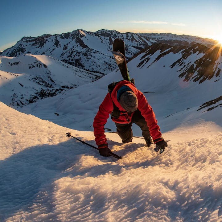 Photograph by Jeff Cricco of a man scaling a snowy mountain with skis on his pack
