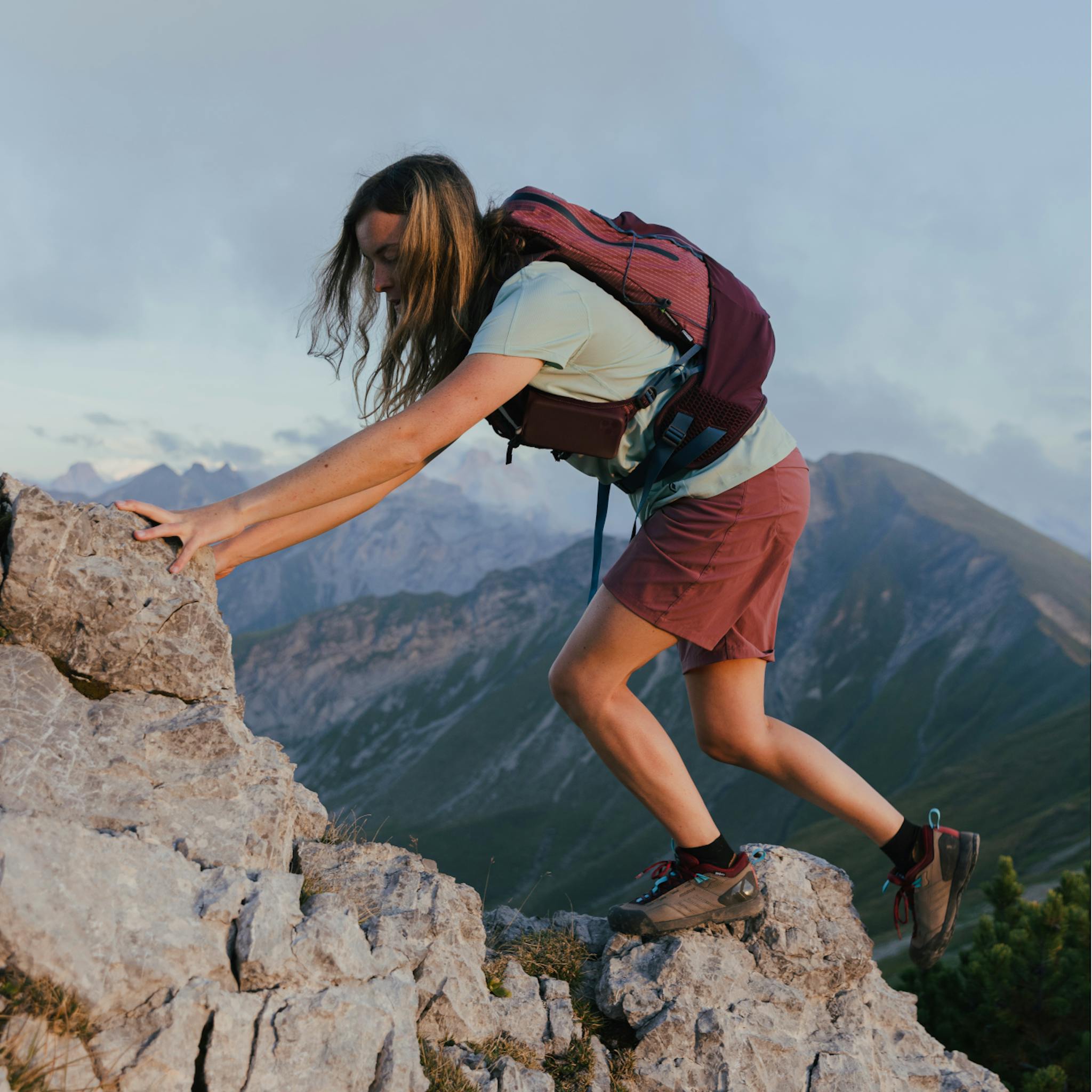 Woman scrambling up a ridge wearing Mission Leather shoes