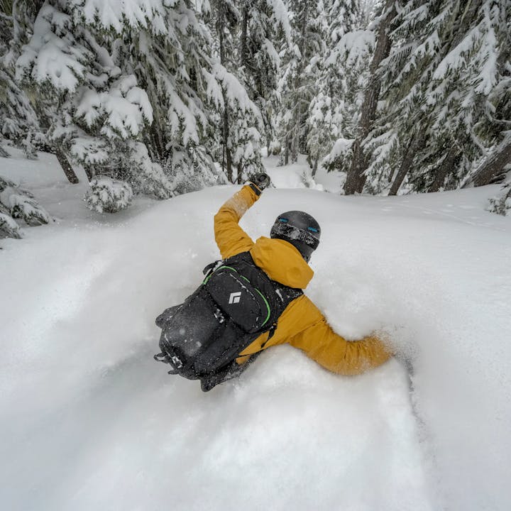Skier in deep powder skiing with the new Black Diamond Dawn Patrol 25L Backpack