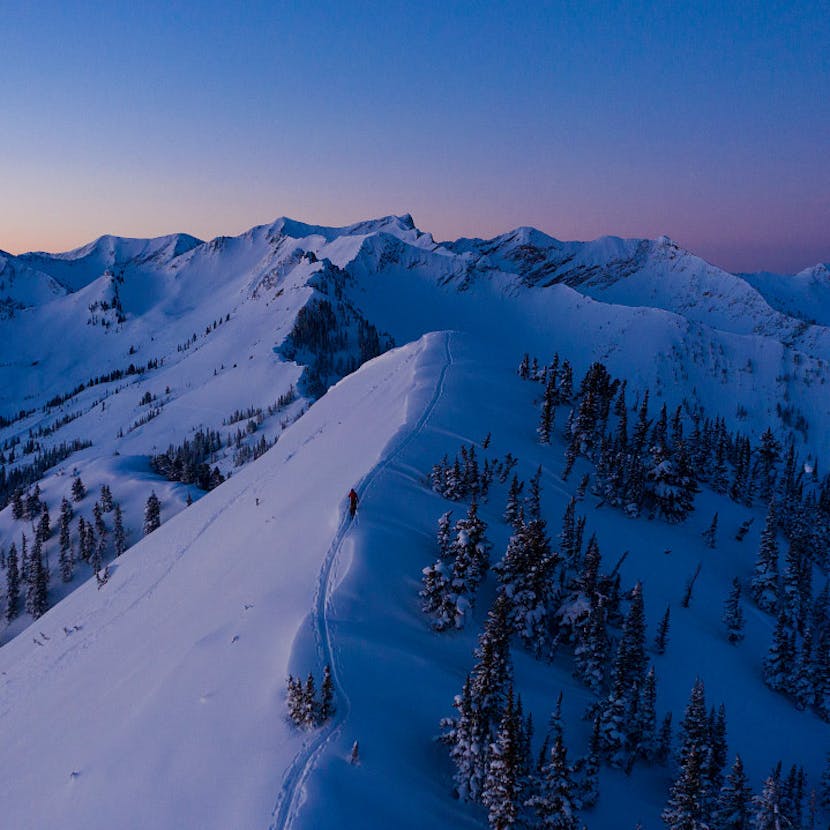 Skier touring along a ridgeline at dawn.