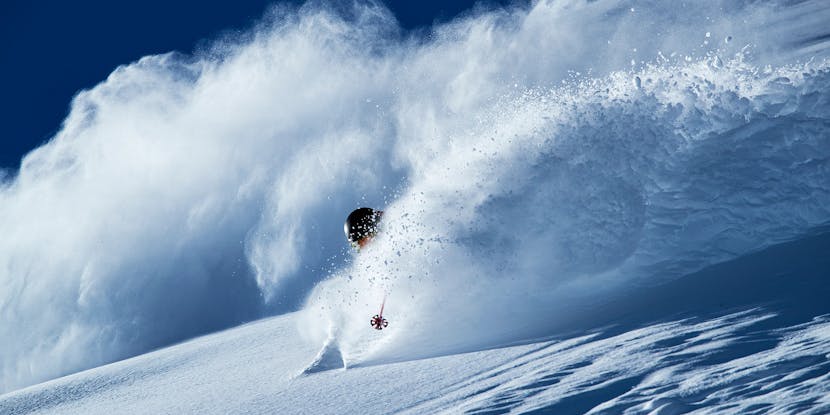 Skier spraying snow on a turn in the backcountry.