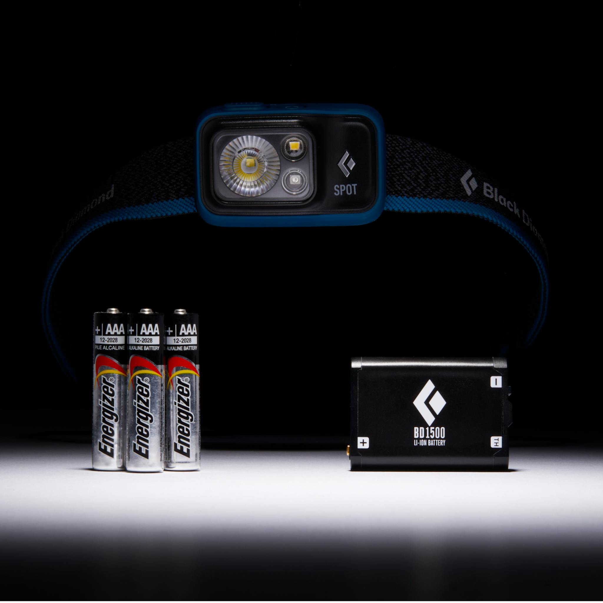 A picture of the Spot 400 Headlamp with three AAA batteries on the left and a BD 1500 on the right.
