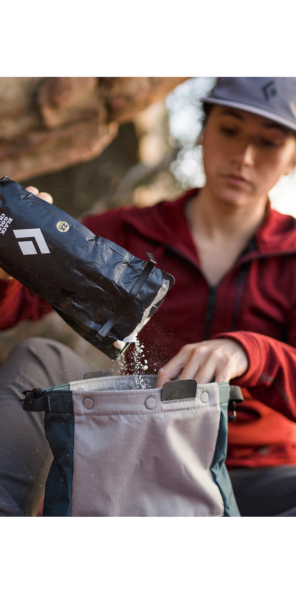 Climber at a boulder pouring Black Diamond Black Gold Chalk into a chalk bag