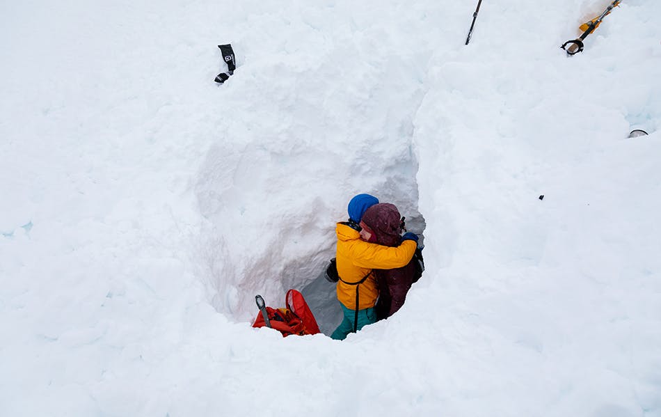 two skiers hugging after they made the rescue from the snow hole