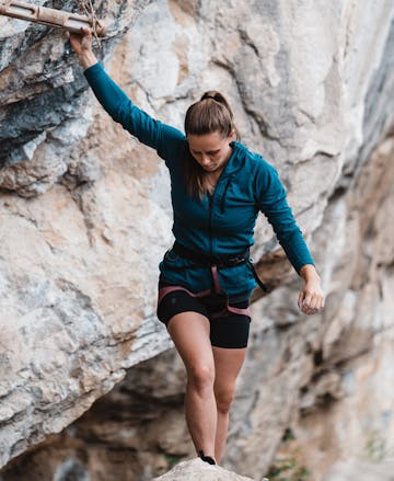 A climber warms up on a hang board wearing the Black Diamond Coefficient Fleece hoody.