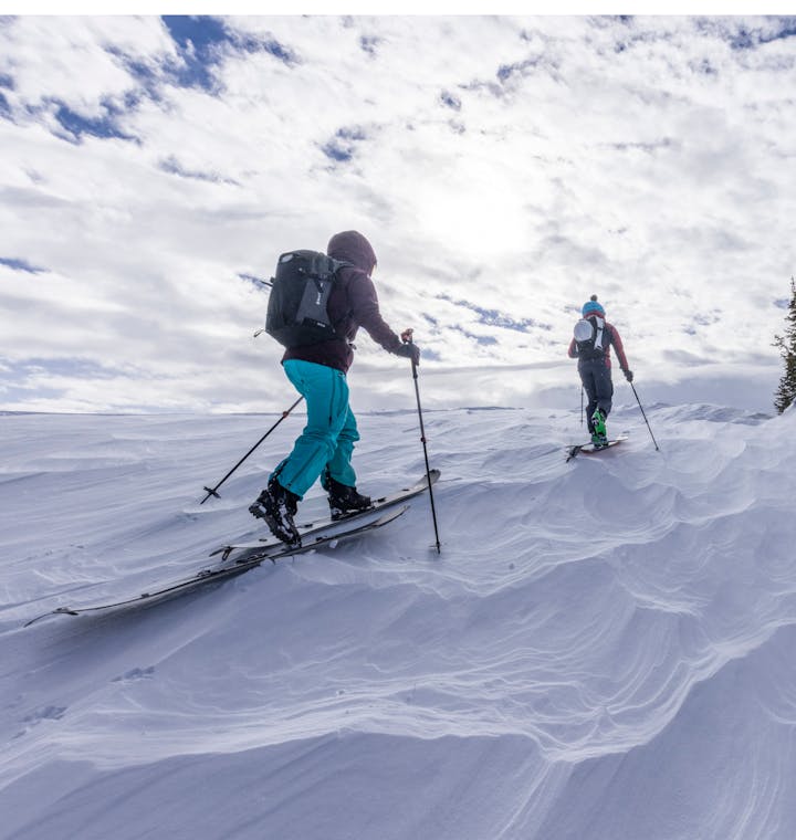 A couple of backcountry skiers on a skin track on a bluebird day. 