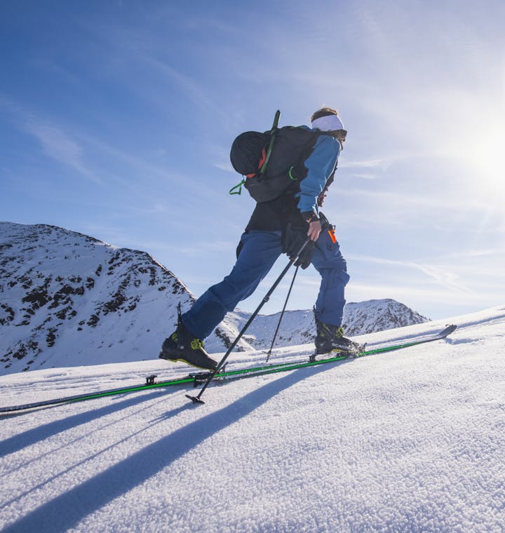 A backcountry skier skinning on a sunny spring day. 