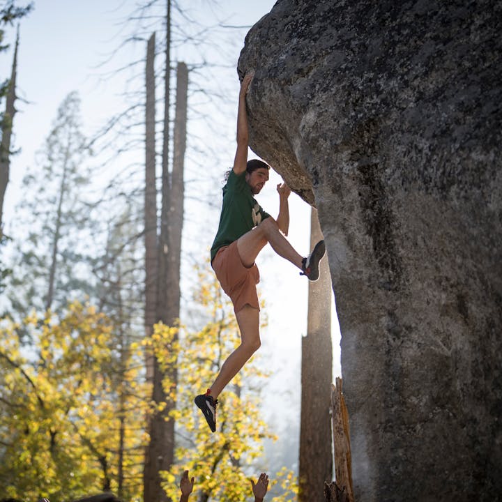 A climber completes the crux of their boulder problem wearing Black Diamond Aspect Pro climbing shoes and the Dirtbag shorts. 