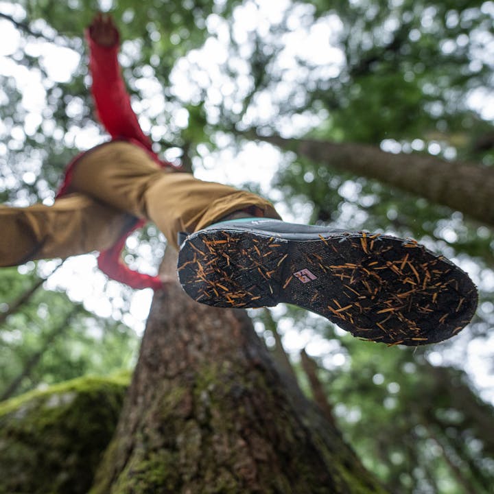 A hiker steps over a log showing the bottom of Black Diamond Approach Shoes. 