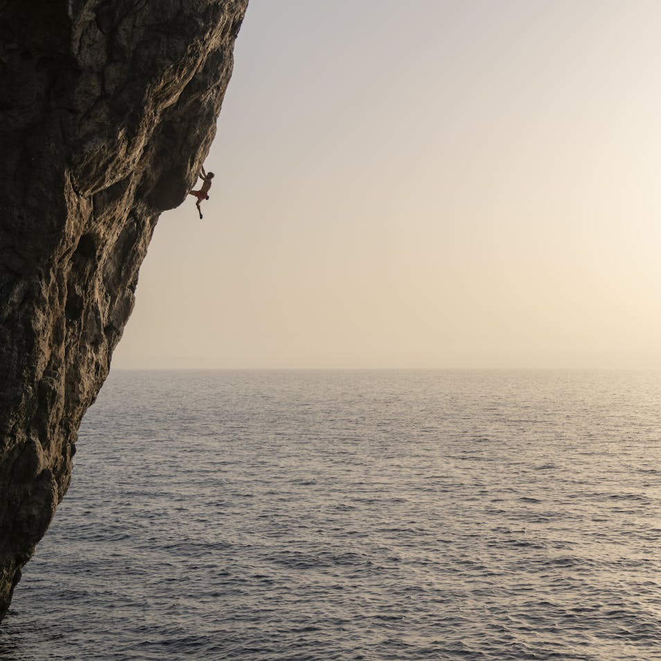 Climber climbing, ocean in background