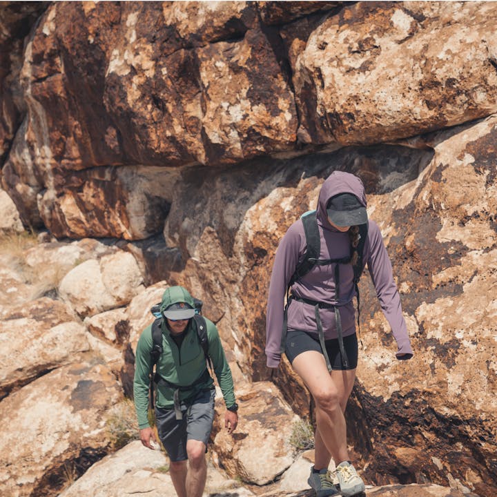 Two hikers approach a climb in the desert wearing Black Diamond apparel. 