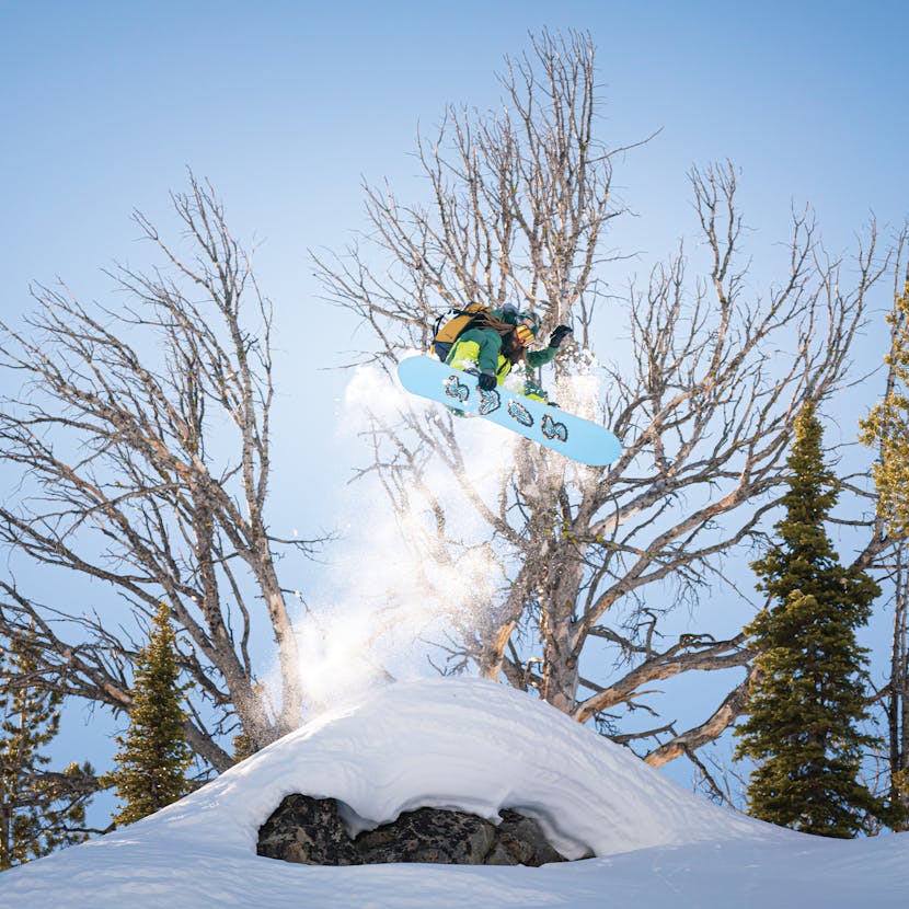 Black Diamond Athlete John Jackson grabs a board over a snow covered cliff