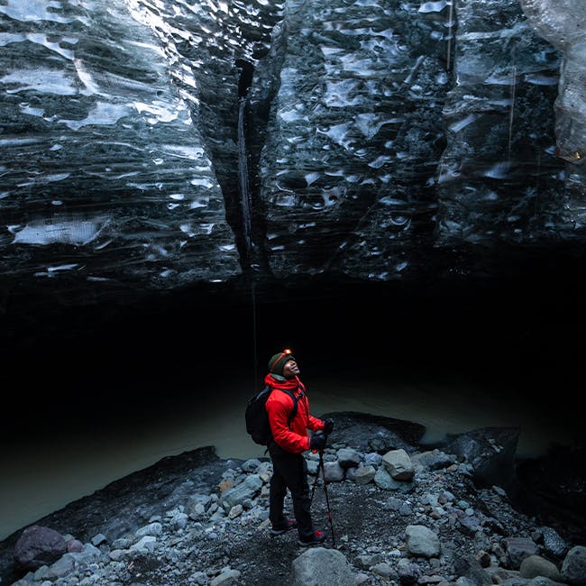 Black Diamond Ambassador Andre King stands in an ice cave wearing the Highline Stretch shell and pant. 
