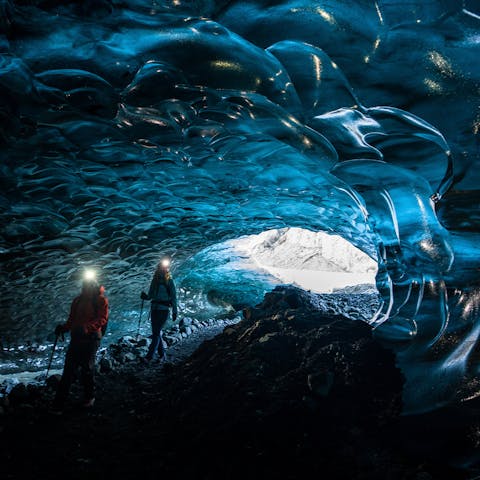 Two hikers walking through an ice cave in Black Diamond apparel. 