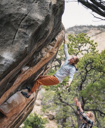 A climber wears the First Light hybrid Hoody to attempt a boulder problem.