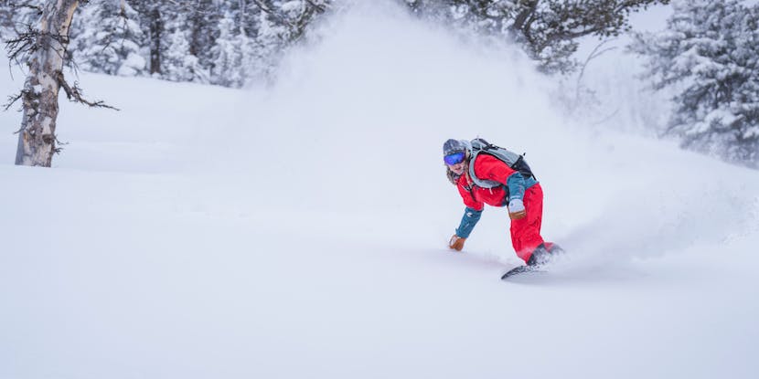 A Snowboarder making pow turns in the backcountry. 
