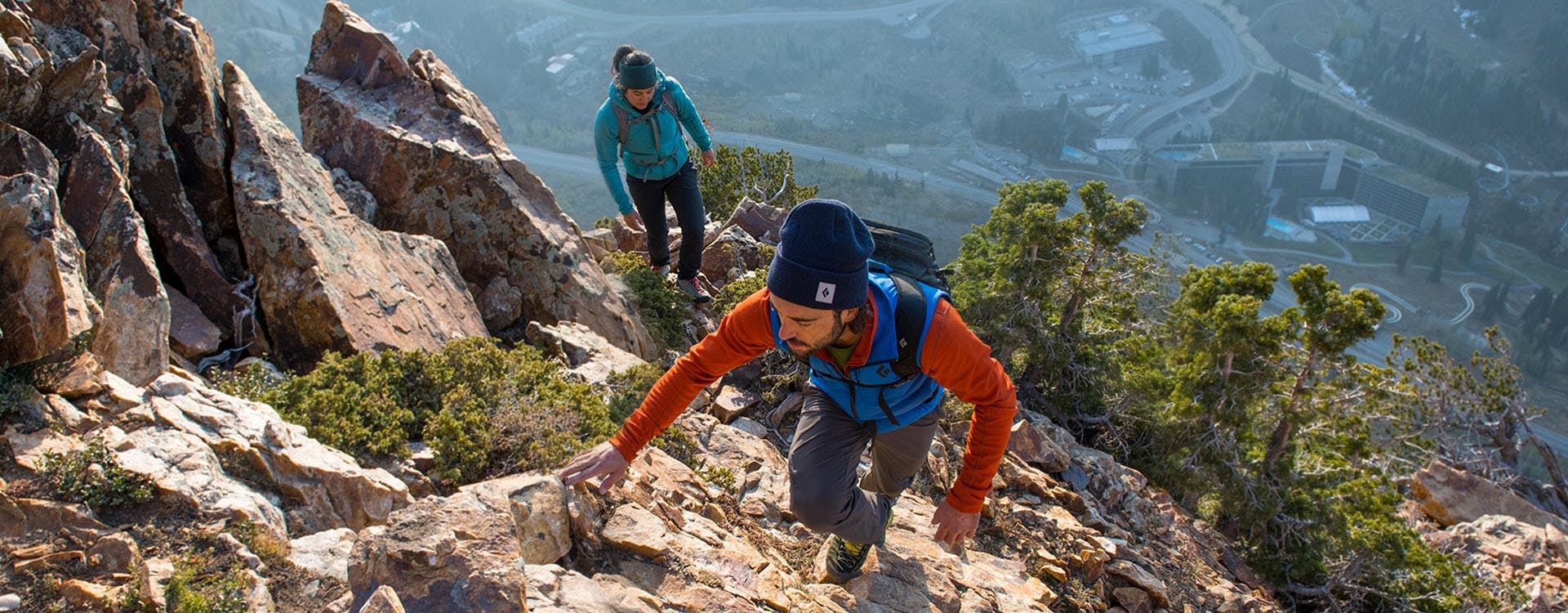 man and woman climbing a ridge