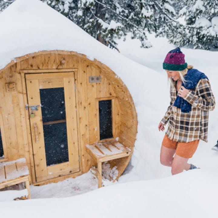 Three skiers get ready to enter a backcountry sauna. 