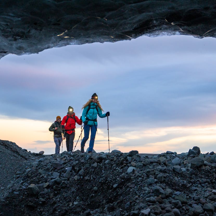 Three Hikers trekking along a glacier at sunset in Iceland wearing Black Diamond Headlamps.