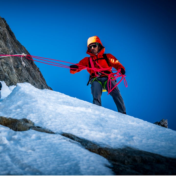 Climber wearing a Black Diamond shell jacket, belays his partner to the to of a pitch.