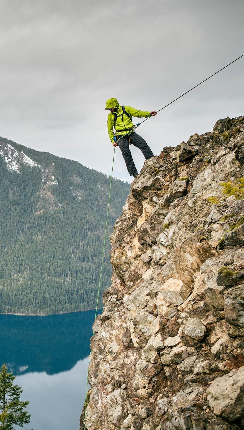 A man repelling while wearing the Stormline Stretch Rain Shell